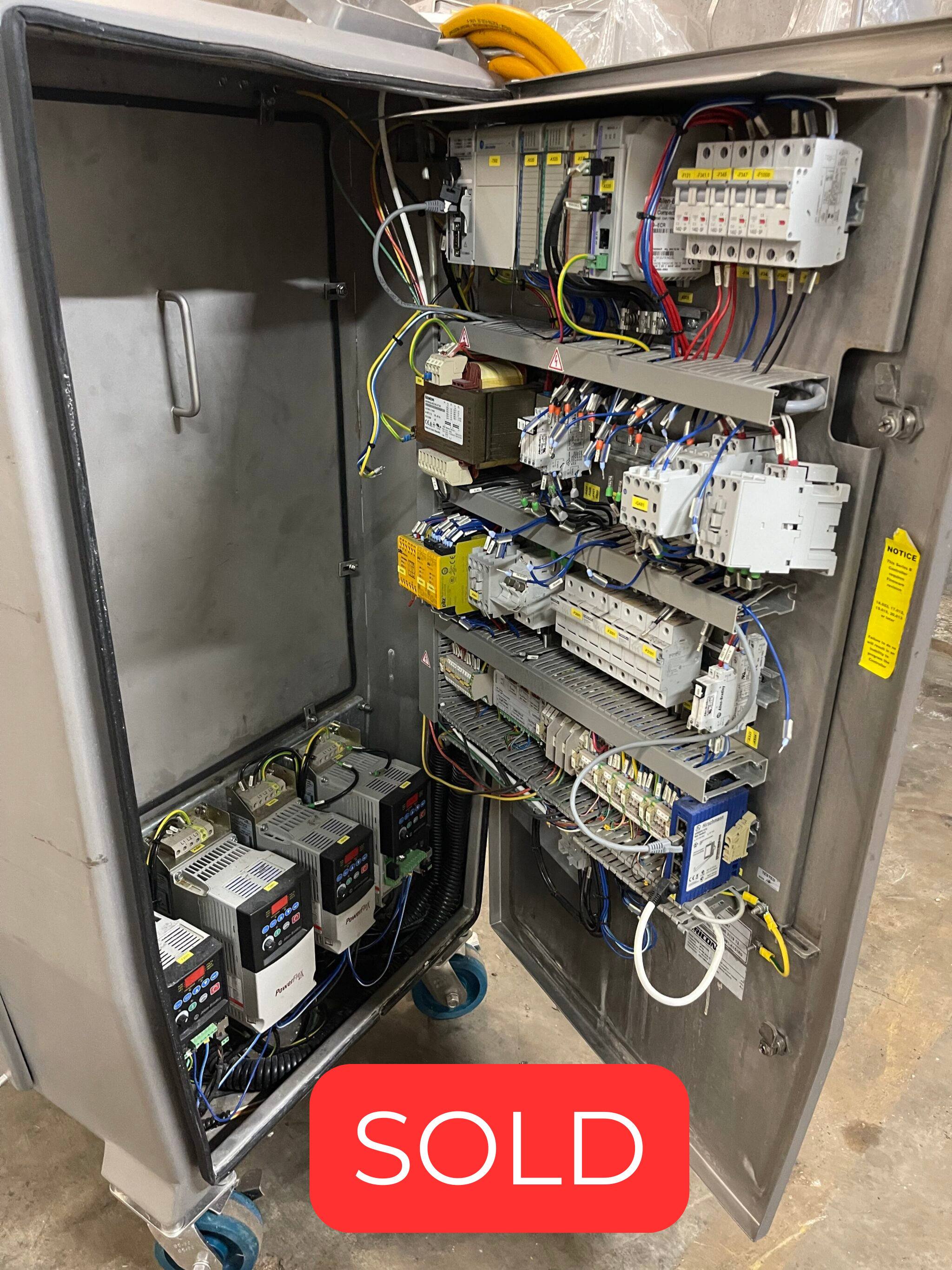 Open industrial electrical control panel with multiple terminal blocks, relays, and colorful wiring inside a metal cabinet.